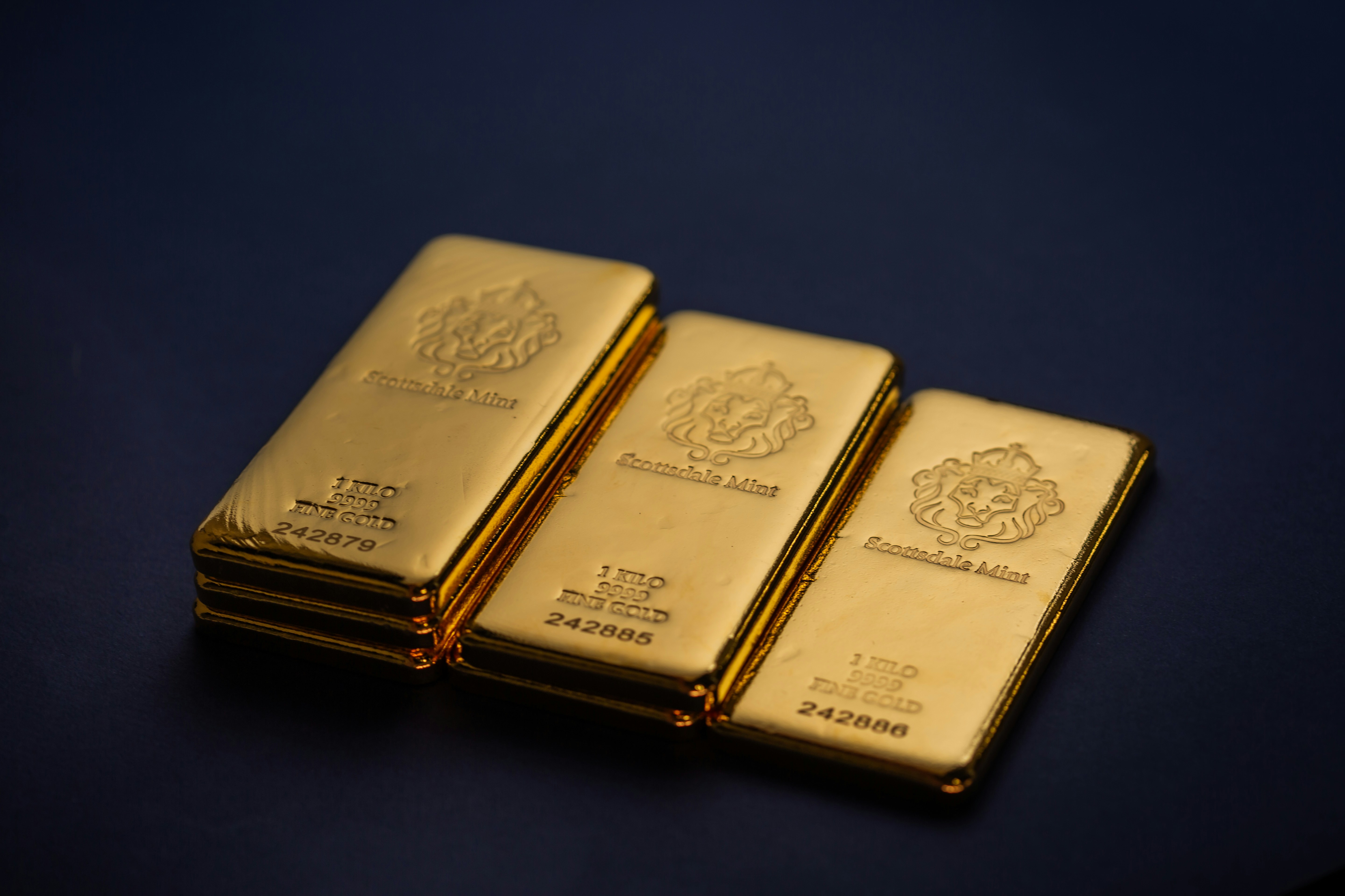 Scottsdale Mint 1 Kilo Gold Bullion Bars sitting on a simple textured backdrop. Each bar is pure 9999 Fine and made from gold precious metals. Please give a shoutout to Scottsdale Mint if able! Shop online for the most beautiful bullion at ScottsdaleMint.com!
